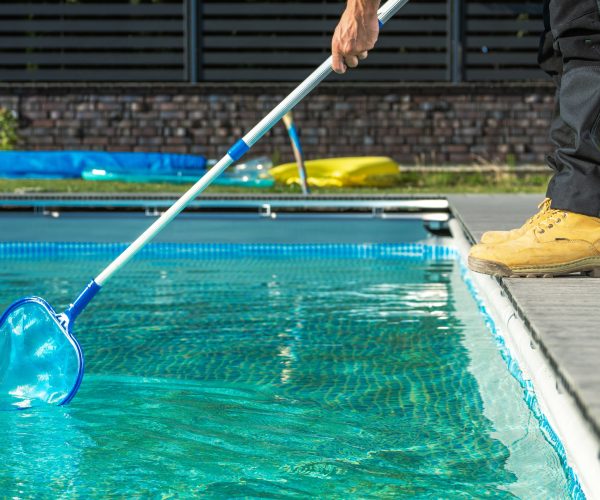Worker with a Pool Net Cleaning Residential Outdoor Swimming Pool Worker with a Pool Net Cleaning Residential Outdoor Swimming Pool